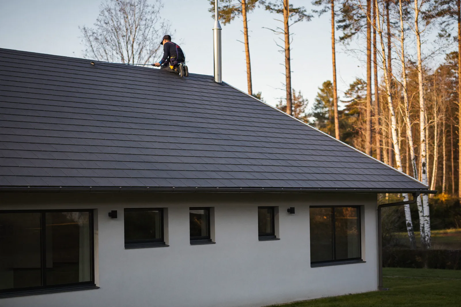 Pinnoitettu tumma tiilikatto omakotitalossa syysvalossa